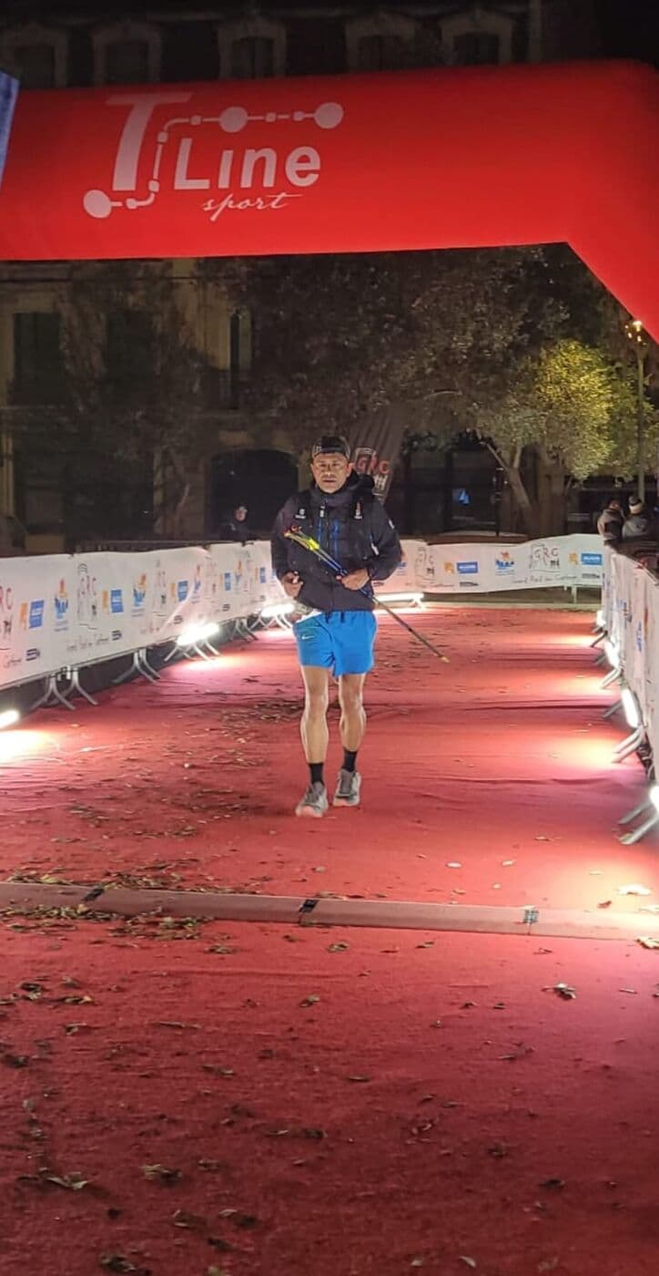 Philippe Ferrer franchit l'arche d'arrivée du Grand Raid des Cathares, de nuit, bâtons en main
