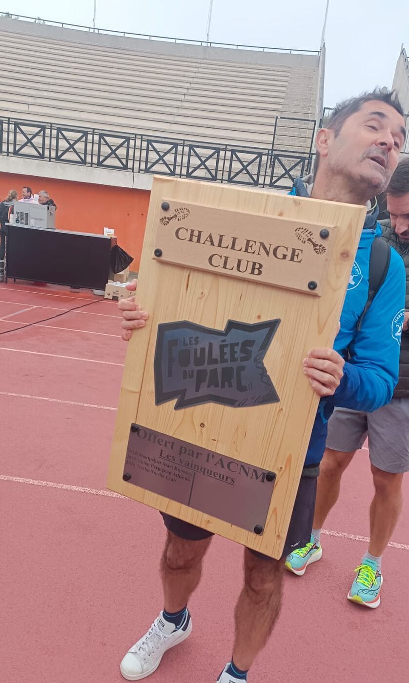 Le trophée en bois du Challenge club des Foulées du Parc, porté par un coureur du club