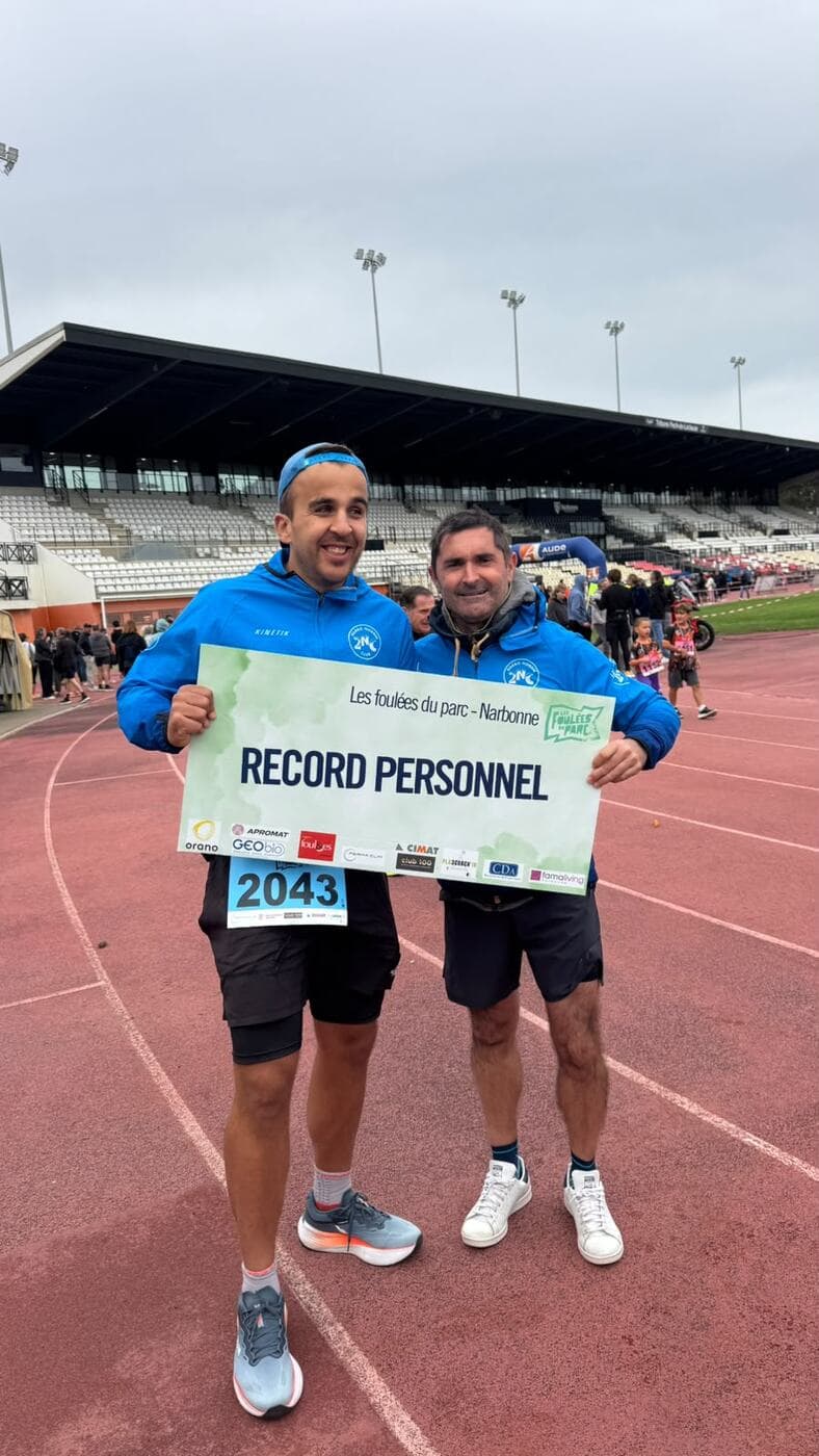 Coureurs du Narbo Nordik Club posant avec le panneau « Record personnel » sur la piste du stade, photo 2 sur 12