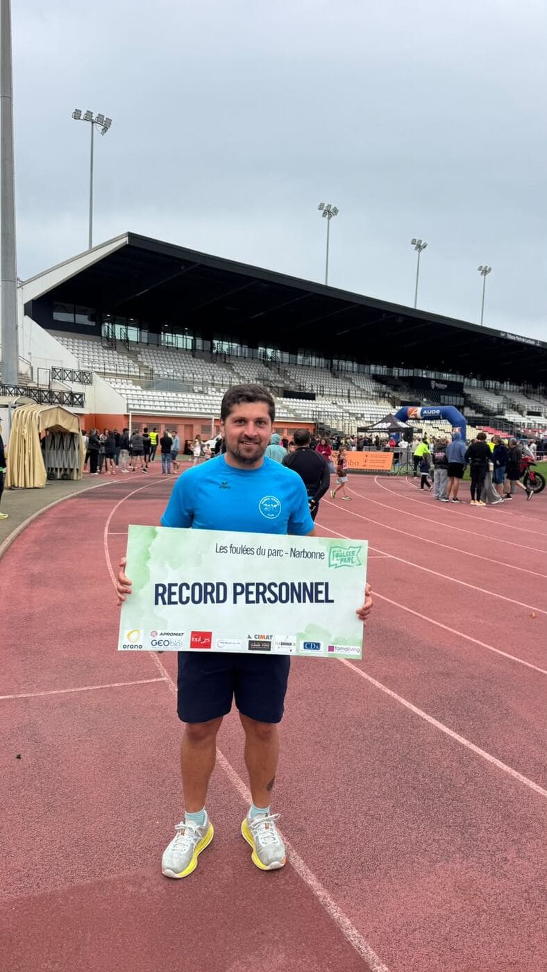 Coureurs du Narbo Nordik Club posant avec le panneau « Record personnel » sur la piste du stade, photo 3 sur 12