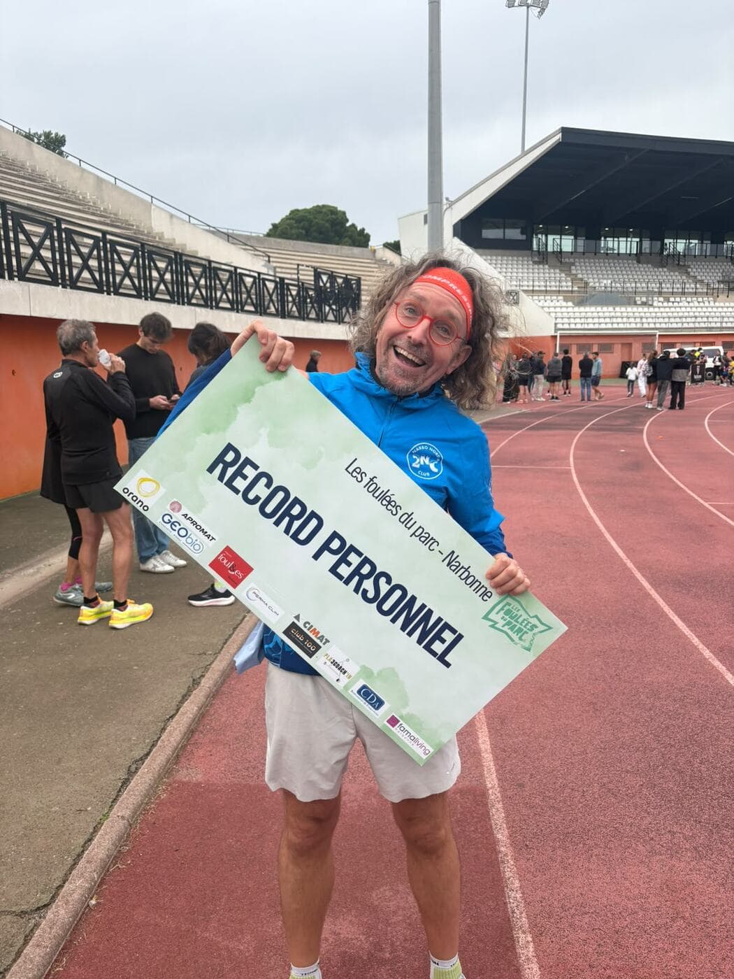 Coureurs du Narbo Nordik Club posant avec le panneau « Record personnel » sur la piste du stade, photo 4 sur 12