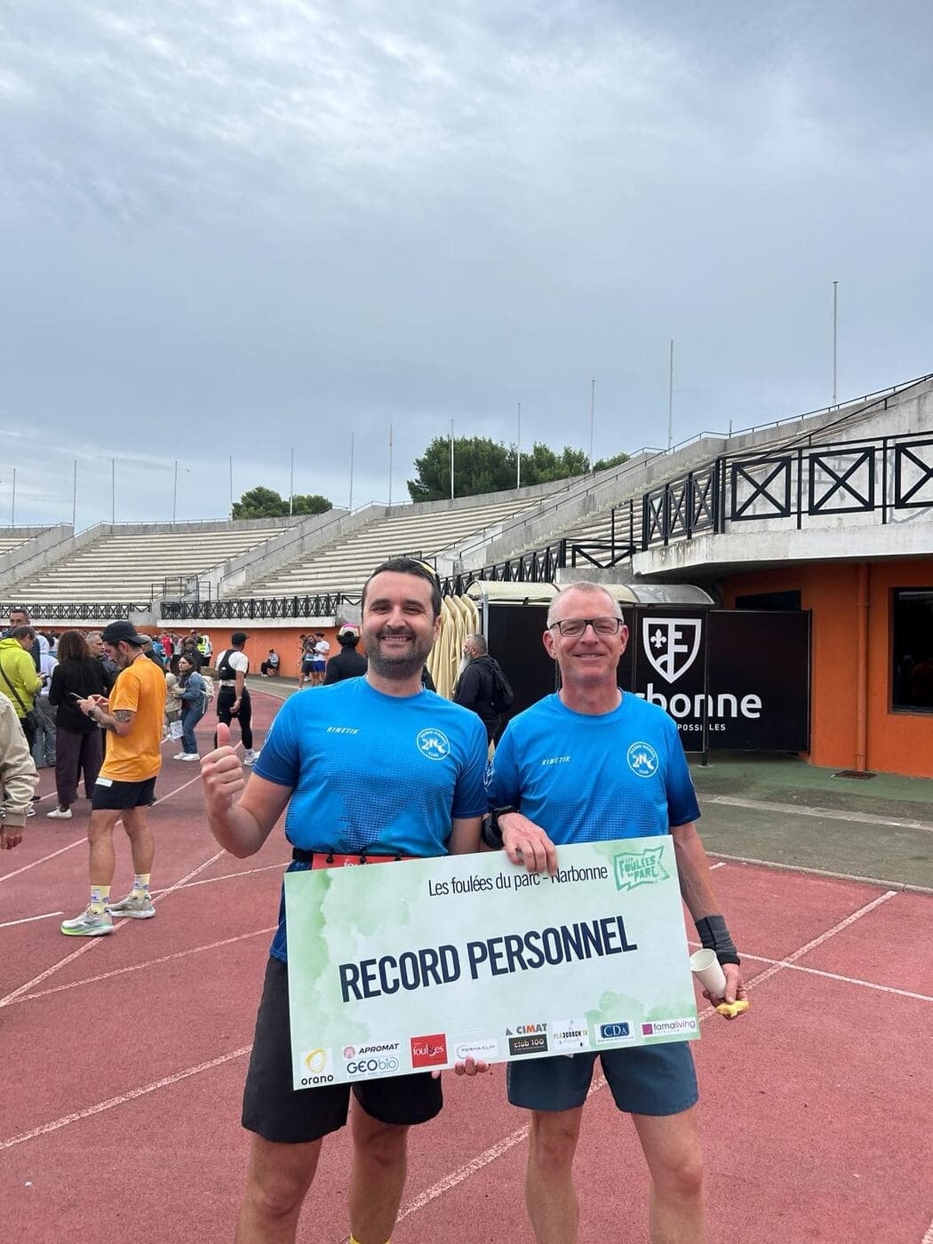 Coureurs du Narbo Nordik Club posant avec le panneau « Record personnel » sur la piste du stade, photo 5 sur 12