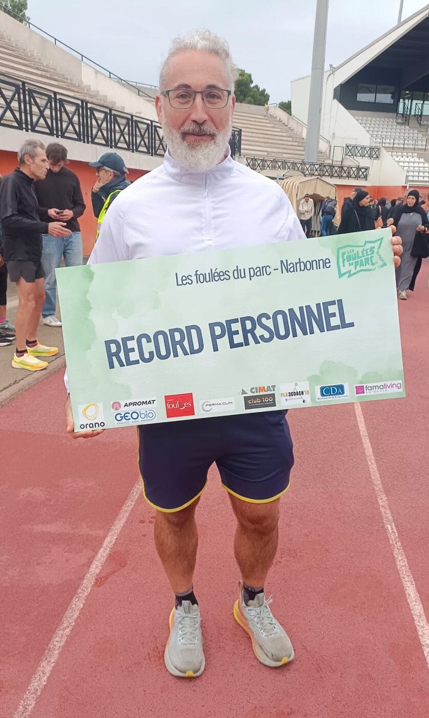 Coureurs du Narbo Nordik Club posant avec le panneau « Record personnel » sur la piste du stade, photo 7 sur 12