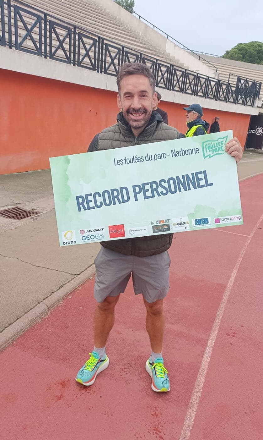 Coureurs du Narbo Nordik Club posant avec le panneau « Record personnel » sur la piste du stade, photo 8 sur 12