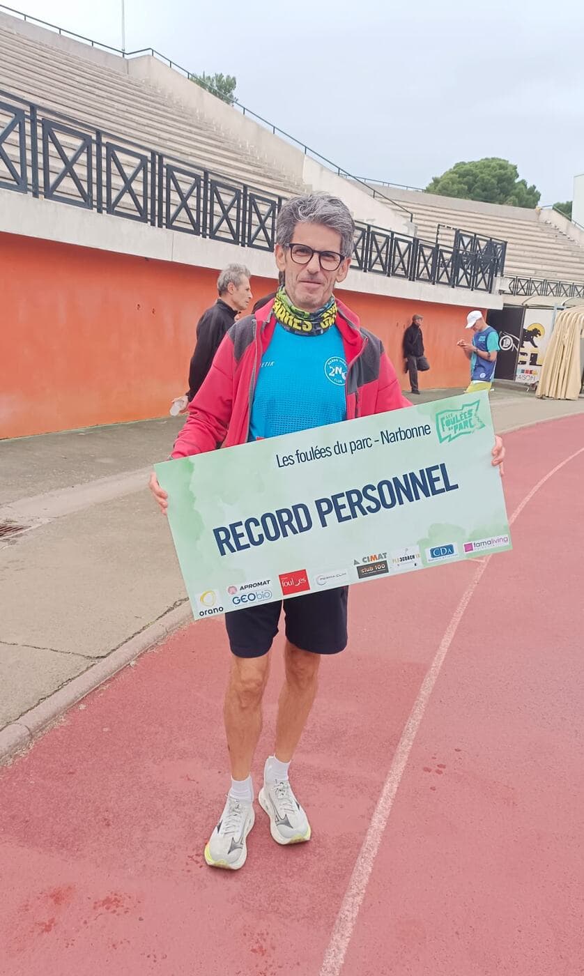 Coureurs du Narbo Nordik Club posant avec le panneau « Record personnel » sur la piste du stade, photo 9 sur 12
