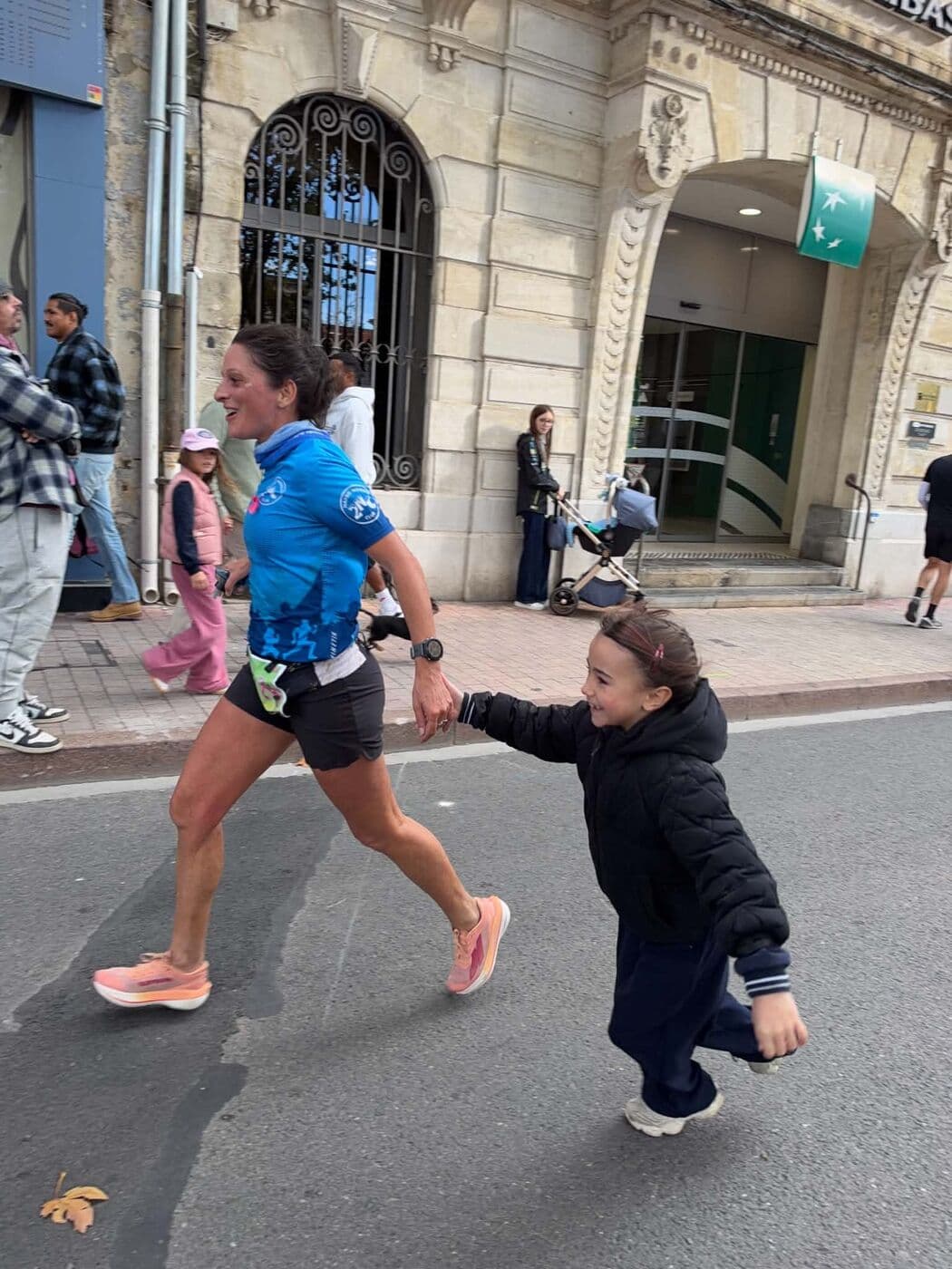 Une coureuse du Narbo Nordik Club tient la main d'une petite supportrice qui court à ses côtés